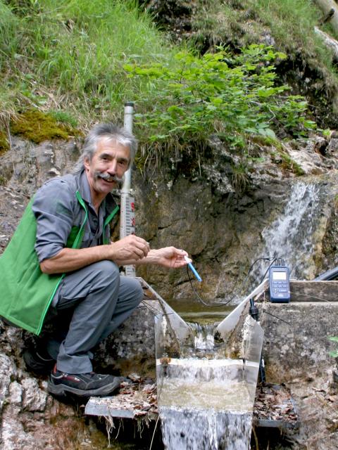 Nationalpark Mitarbeiter misst Wassertemperatur von kleinem Berggerinne in einem Steilgelände