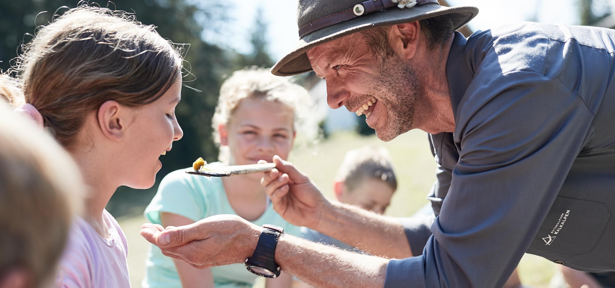 Nationalpark Ranger reicht einem Mädchen Essen auf einem Holzlöffel