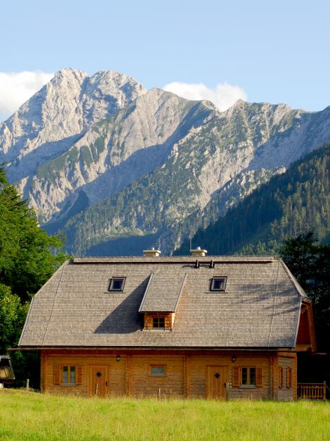 Holzgebäude der Hengstpasshütte im Hintergrund eine felsige Bergkulisse