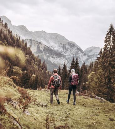 Eine Frau und ein Mann mit Rucksack wandern gemeinsam durch Herbstlandschaft