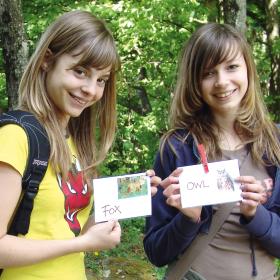 Zwei Mädchen halten englisch beschriftete Tierkärtchen in Händen