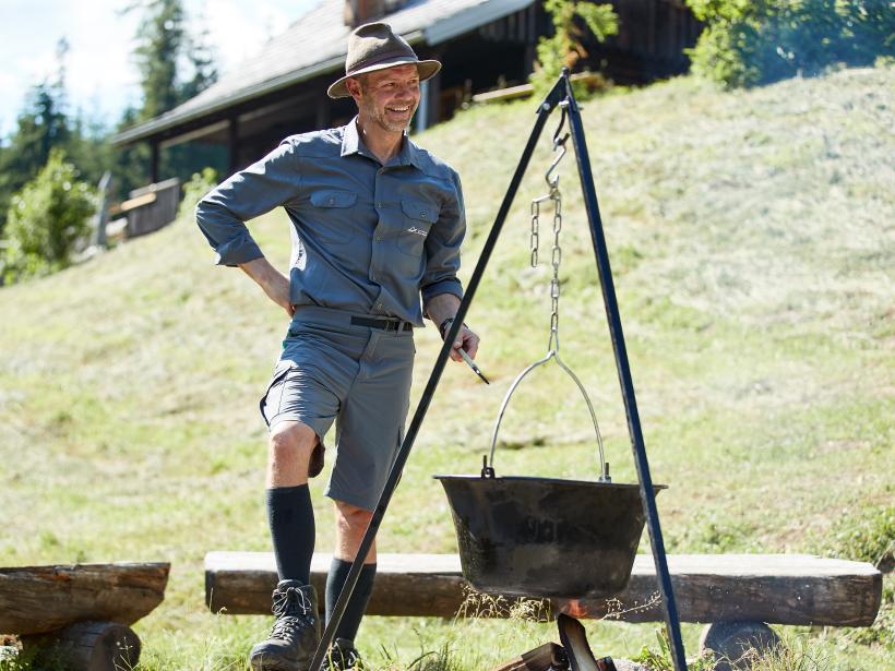 In einem über Lagerfeuer hängenden Kessel kocht ein Nationalpark Ranger