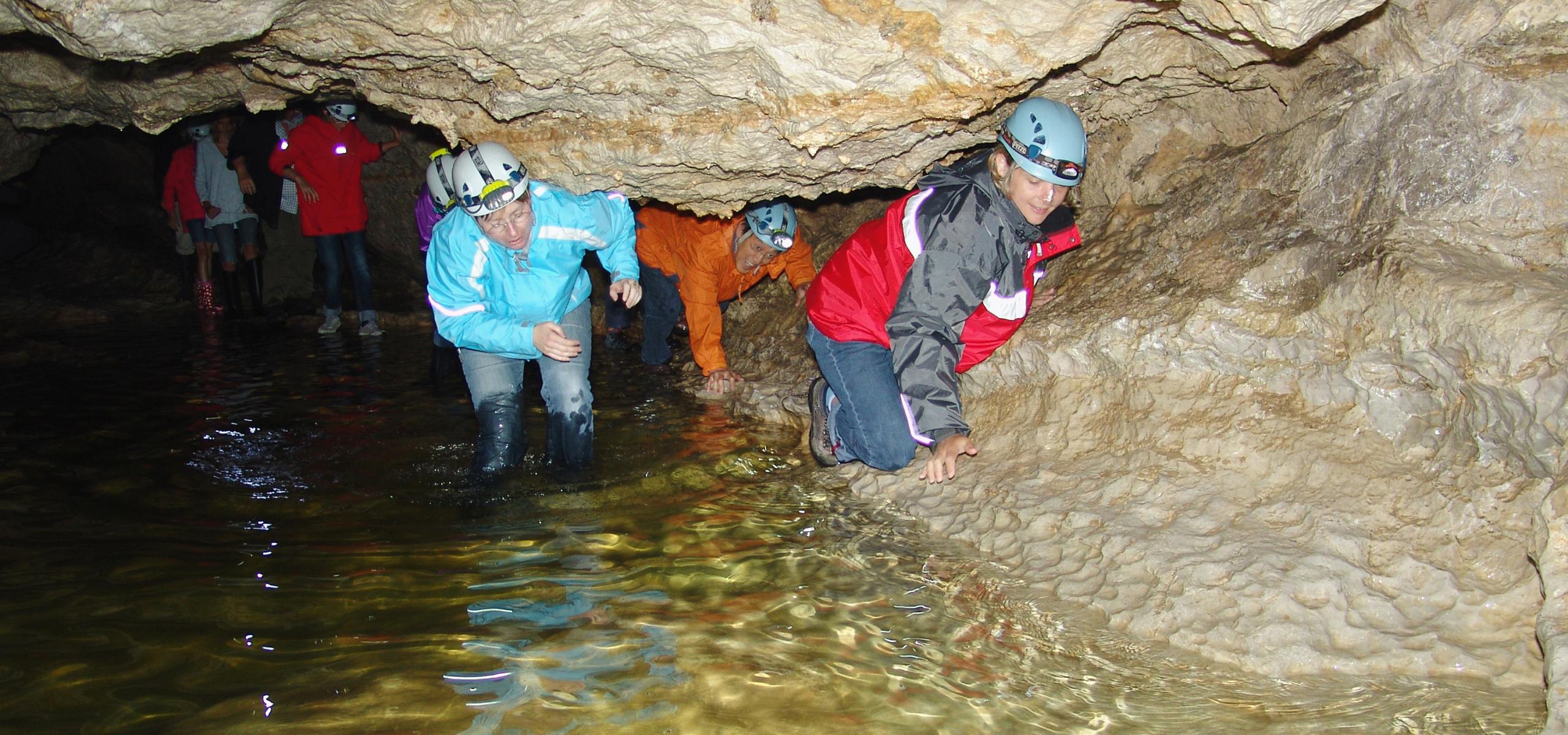 Kinder und Erwachsene drücken sich an Höhlenwand entlang