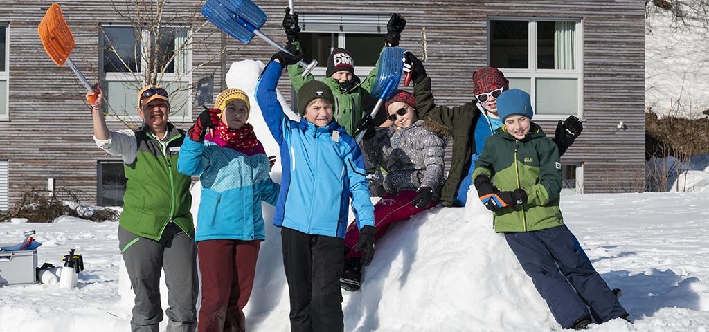 Rangerin und eine Gruppe Kinder bauen eine Schneeskulptur