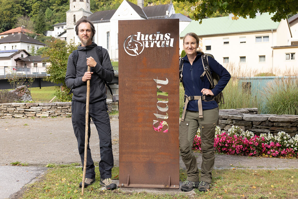 Marc Graf und Christin Sonvilla stehen an einem Eisenmonument mit dem Schriftzug Luchs Trail Start.